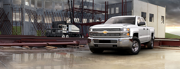Front view of a silver Chevrolet Silverado 2500, highlighting its bold grille and robust body structure against a natural backdrop.